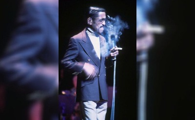 Sammy Davis Jr exhaling cigarette smoke mid-performance