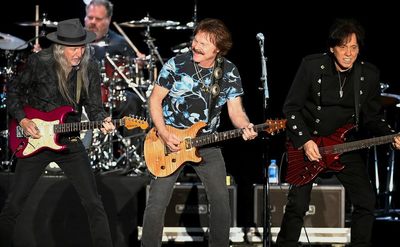 Patrick Simmons, Tom Johnston, and John McFee perform on stage.