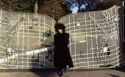 Boy George standing in front of the gate with musical notes 